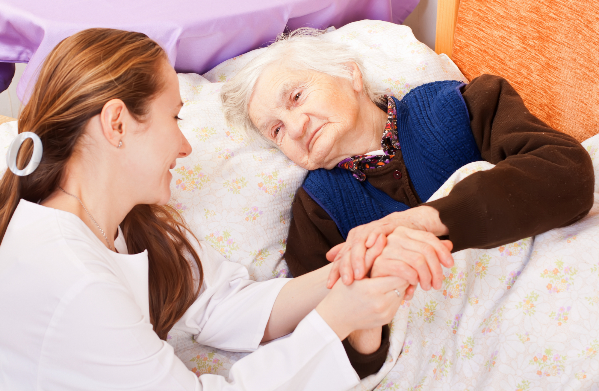 Young doctor holds the old woman's hands