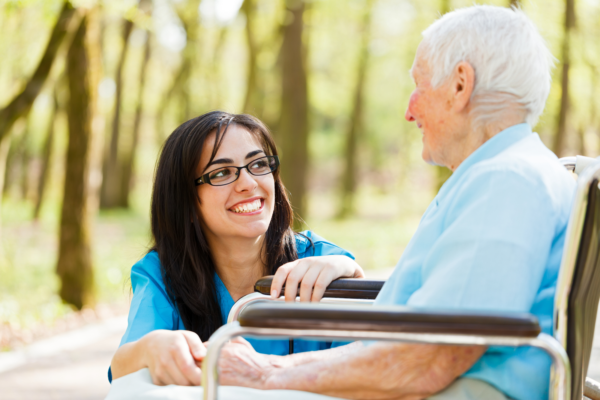 Kind nurse laughing with elderly patient in wheelchair.